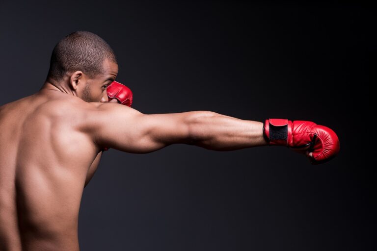 Vue latérale d'un jeune homme torse nu portant des gants de boxe faisant de l'exercice debout