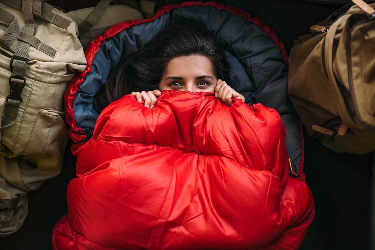 Une jeune femme dans un sac de couchage confortable dans une tente, vue de dessus. Un touriste dans un sac de couchage.